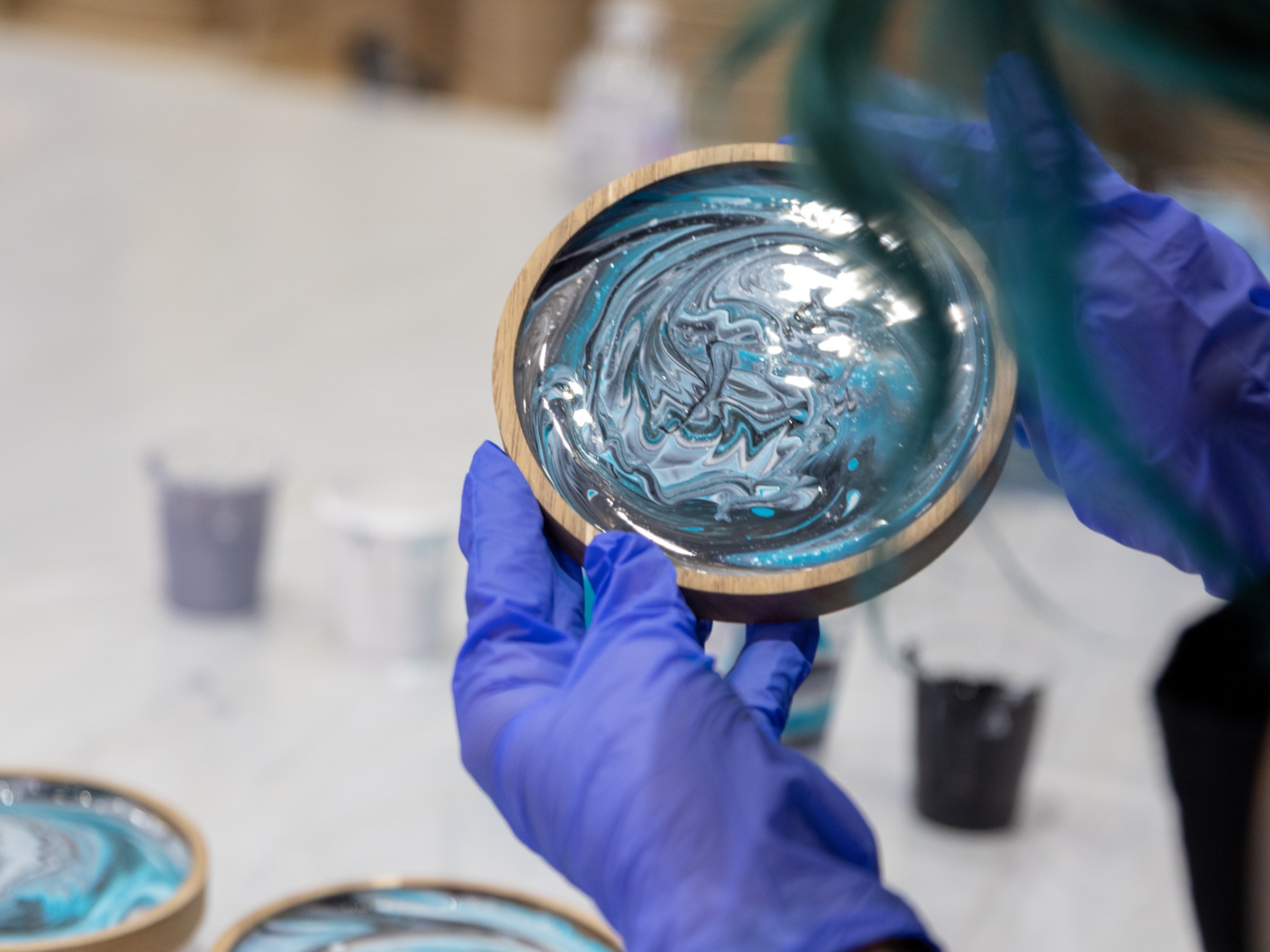 Person with gloves holding a wooden dish with blue and white swirl pattern.