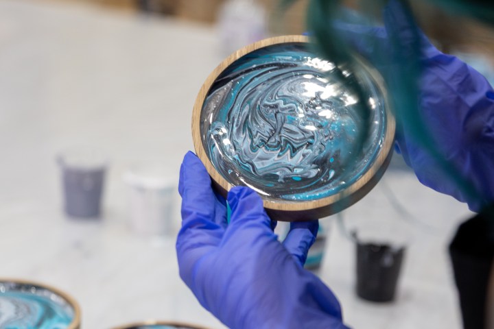 Person with gloves holding a wooden dish with blue and white swirl pattern.