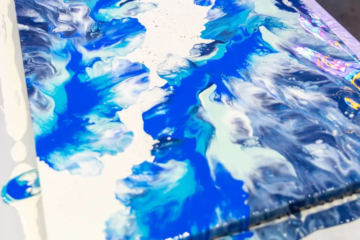 Abstract blue and white fluid art painting on a table.