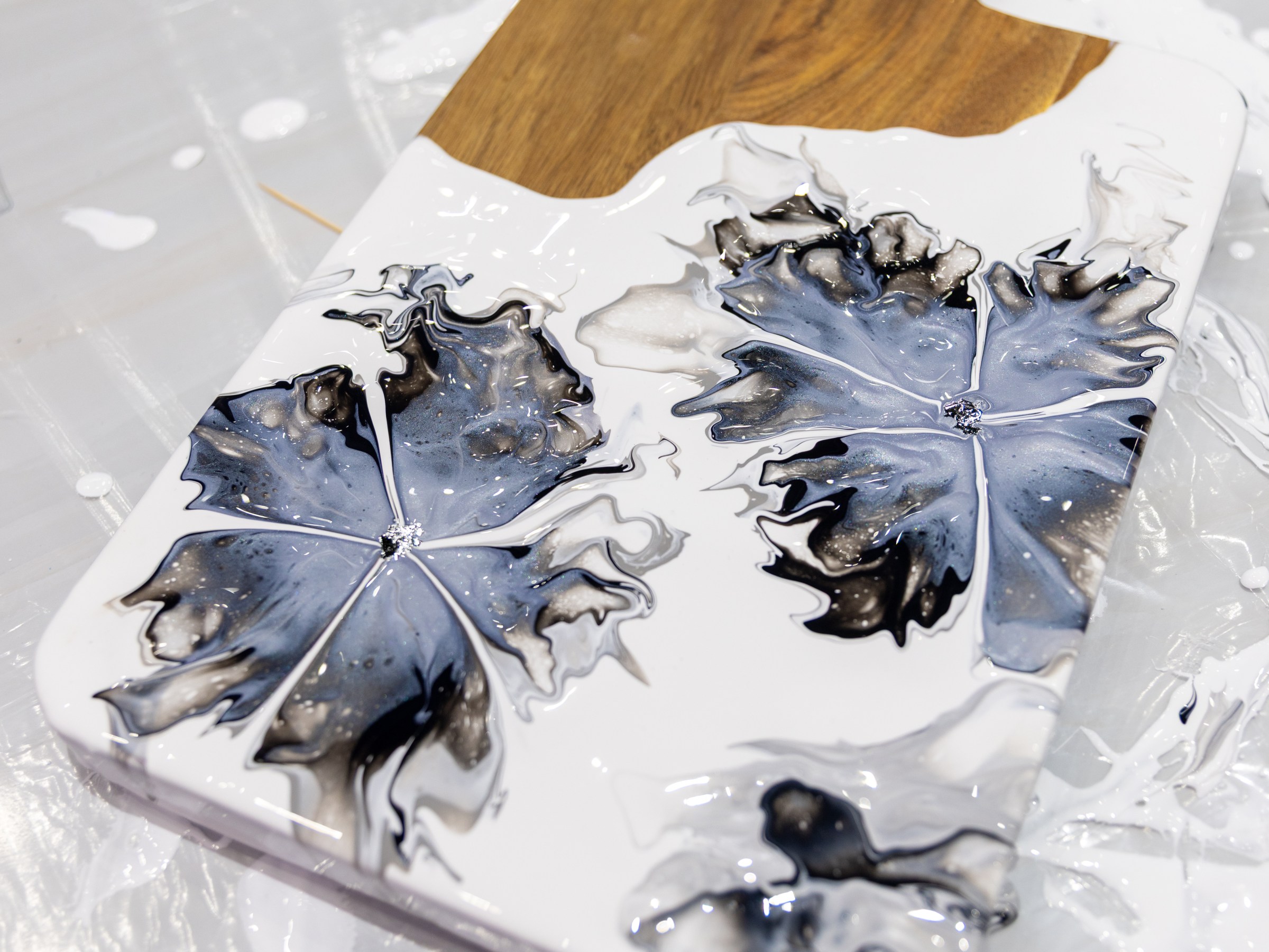 Wood and resin cutting board with abstract black and white floral designs.