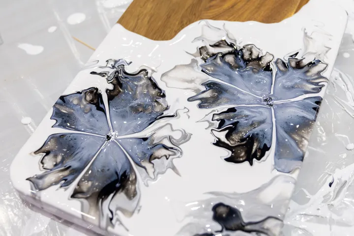 Wood and resin cutting board with abstract black and white floral designs.