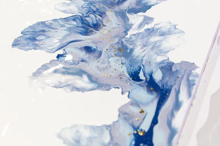 Abstract blue and white painting with gold accents on a rectangular canvas.