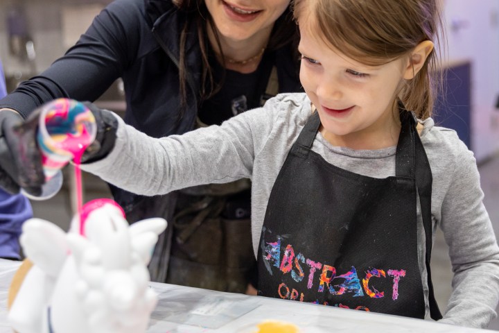 Woman and child painting ceramic unicorn together at a table.