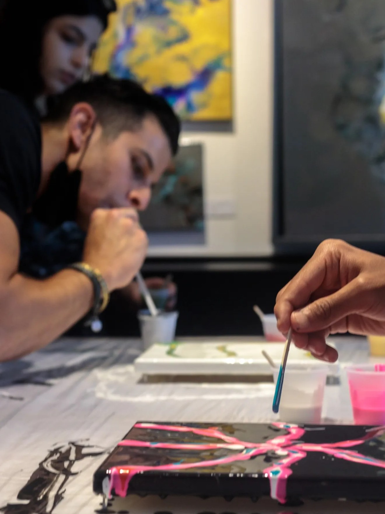 People creating abstract art with paint at a workshop table.