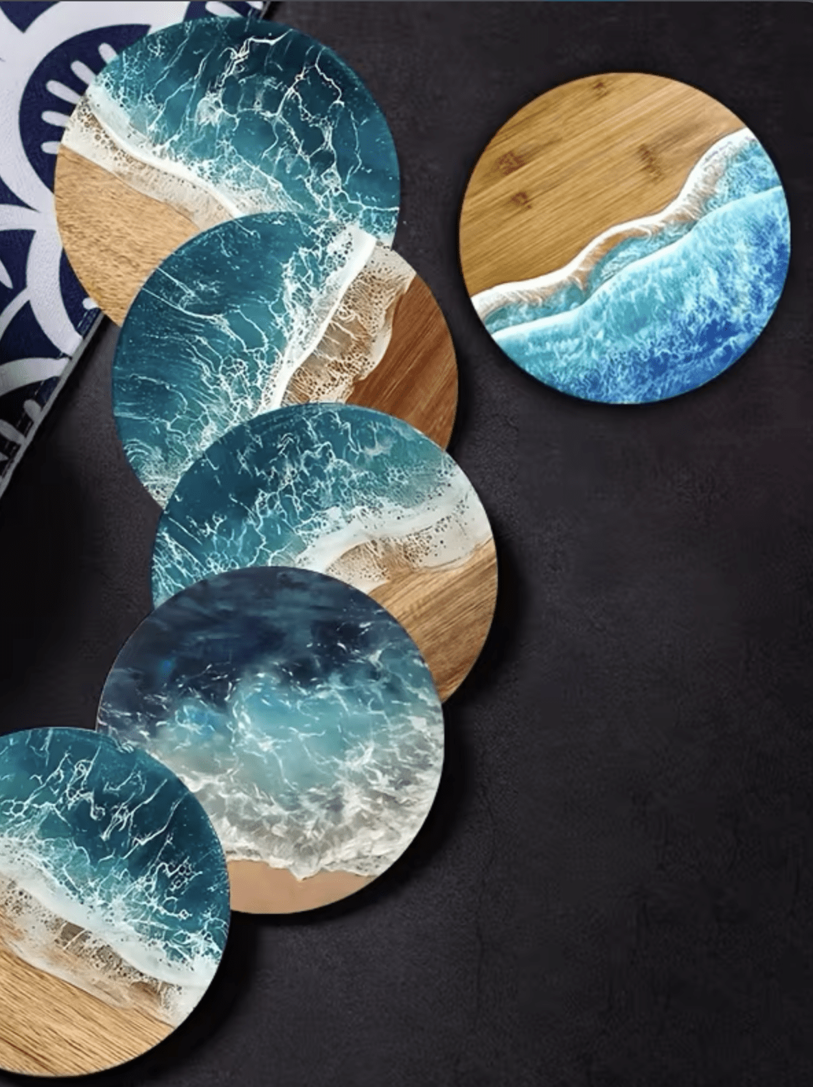 Five round coasters with ocean wave designs on a dark surface, beside a patterned dish.