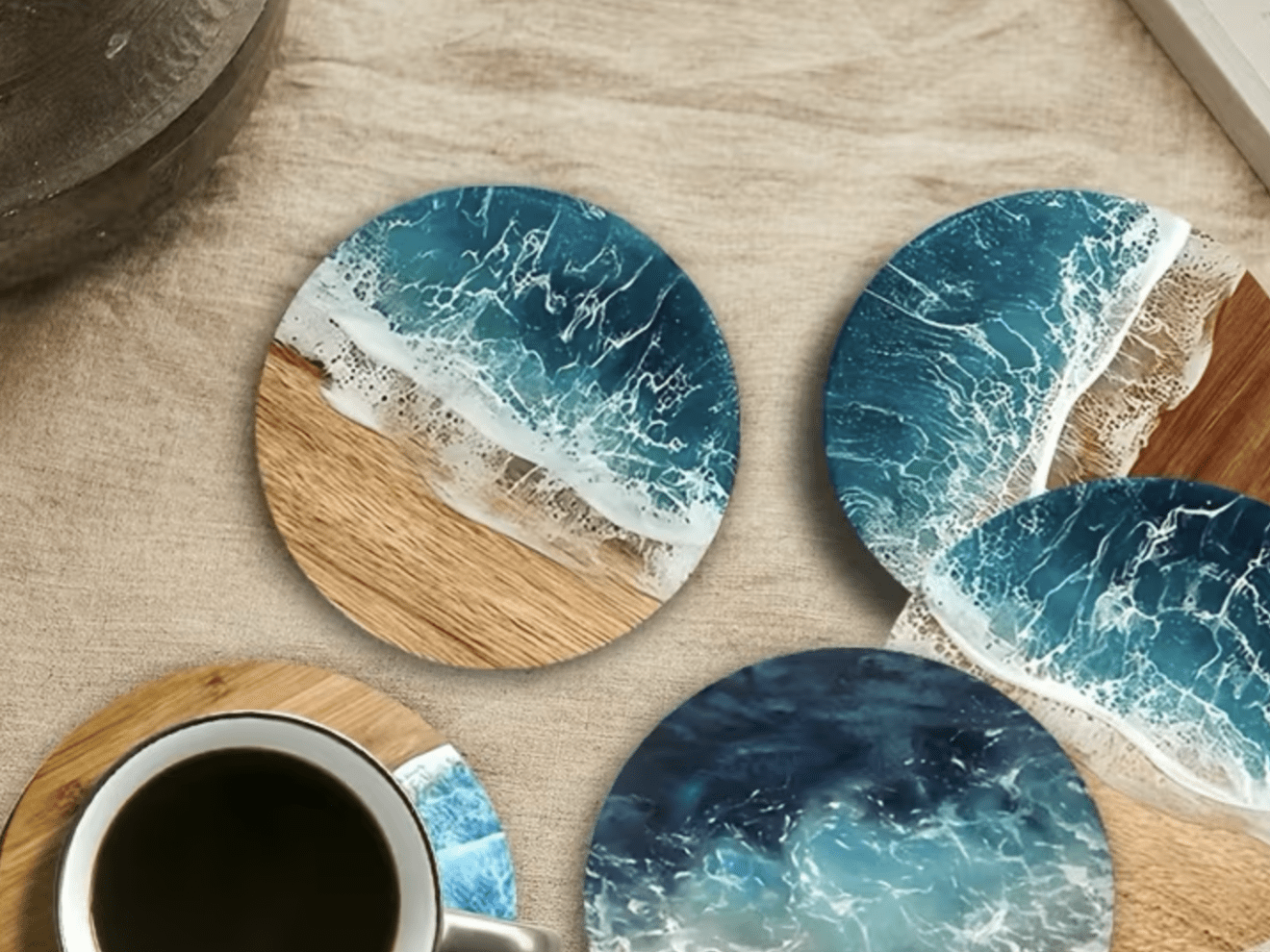 Round coasters with beach and ocean designs, one under a cup of coffee on a table.