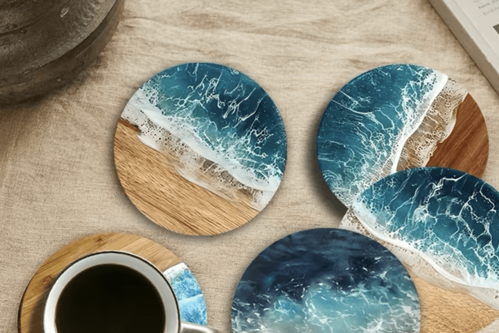 Round coasters with beach and ocean designs, one under a cup of coffee on a table.