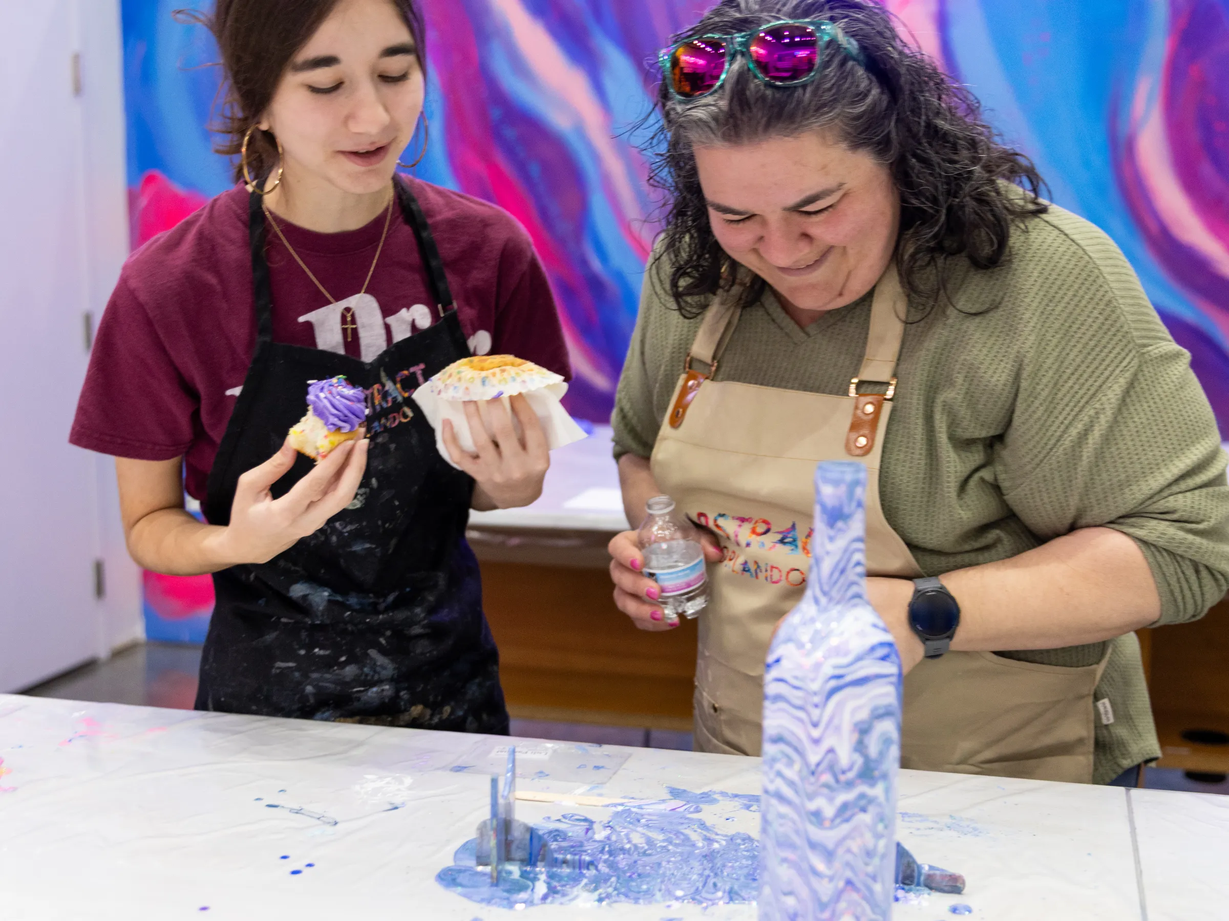 Two people enjoying a pottery painting activity with colorful designs.