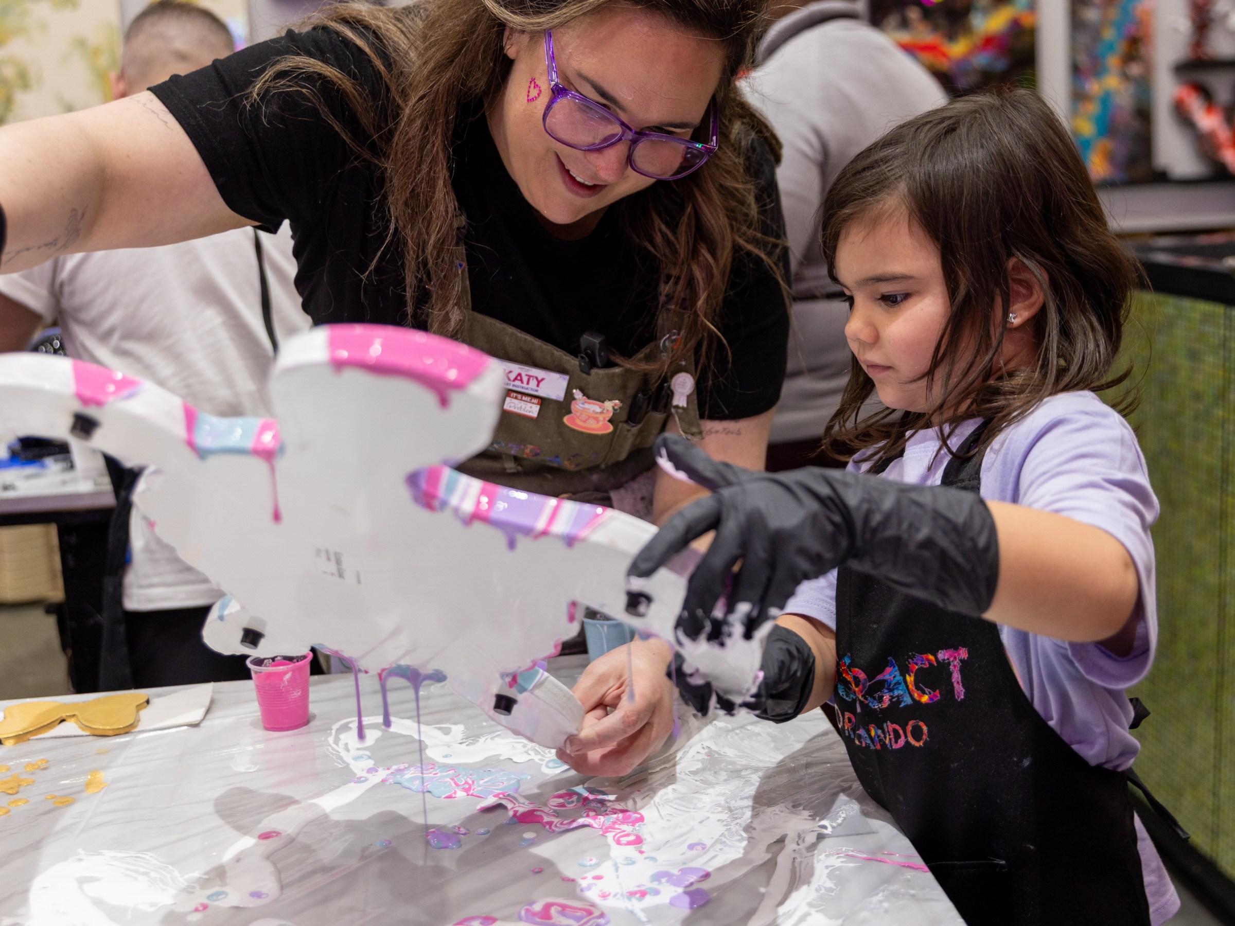 Woman and child painting a craft project together indoors.