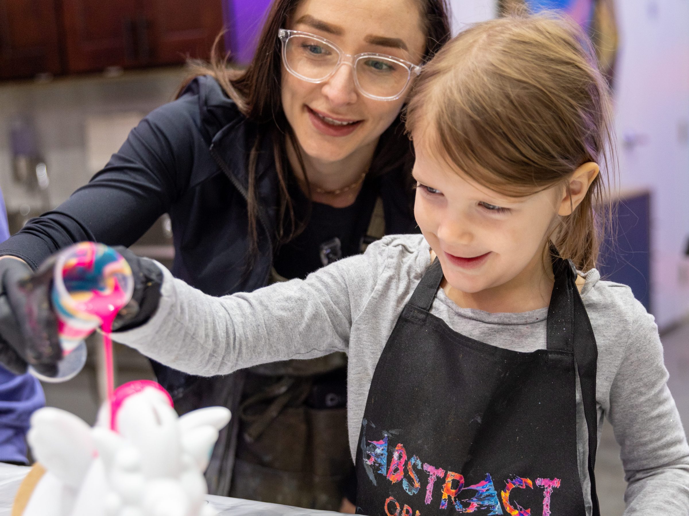 Child and adult painting a ceramic unicorn with colorful paints.