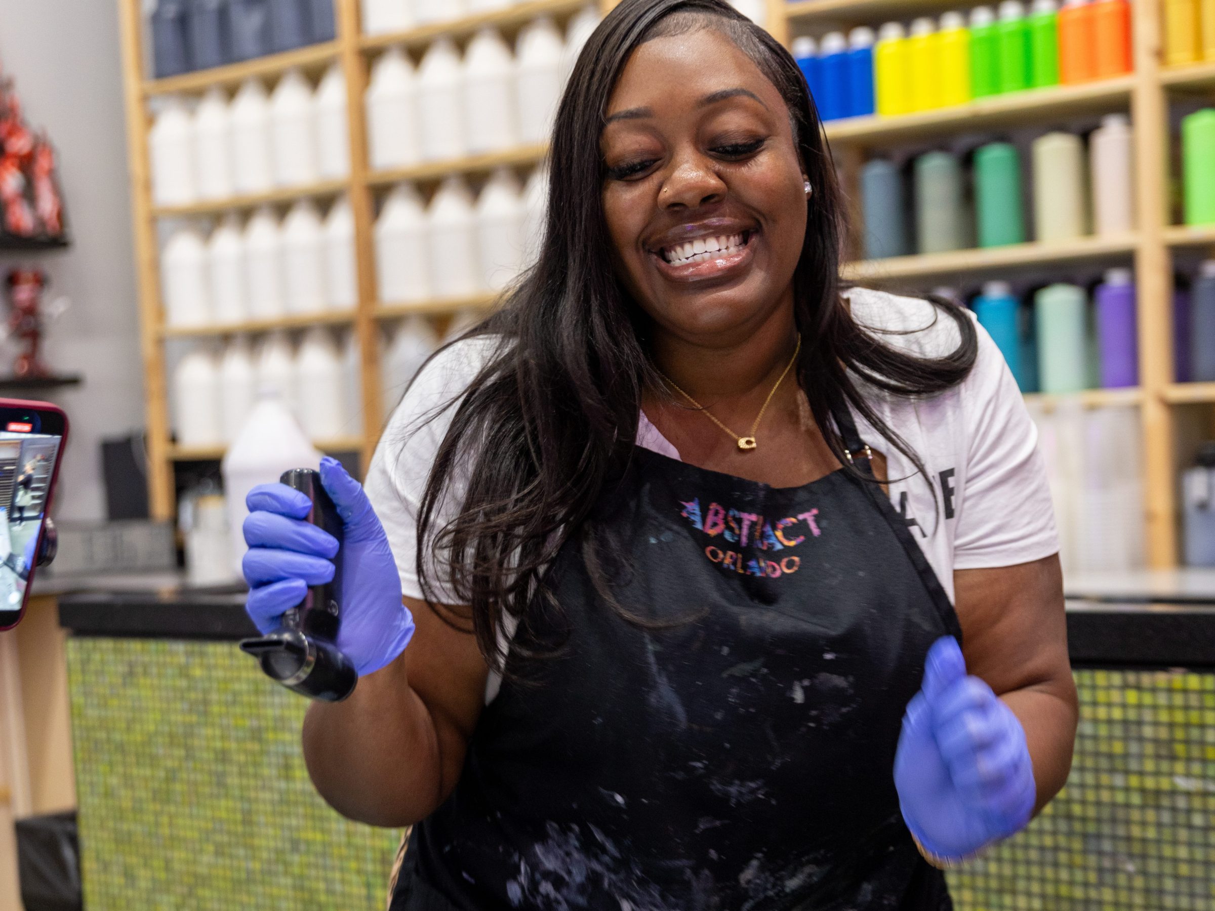 Smiling woman painting with gloves in a colorful art studio.