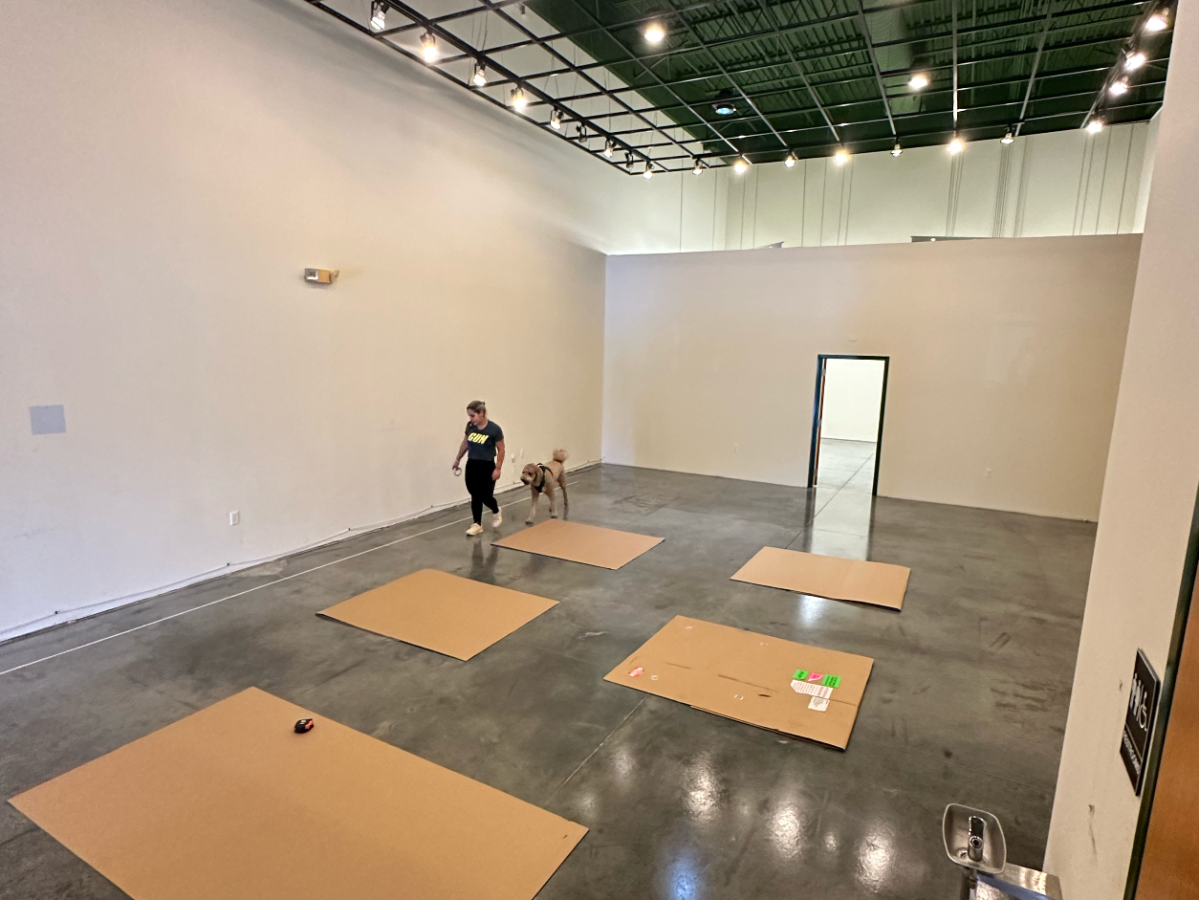 Spacious gallery with person arranging large brown paper sheets on floor.