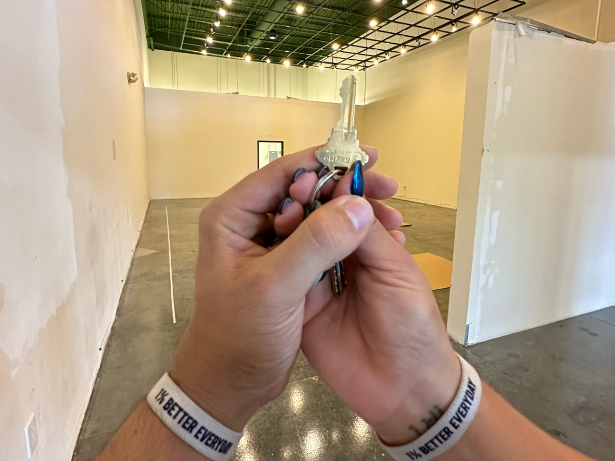 Hands holding keys in an empty room with white walls and green ceiling.