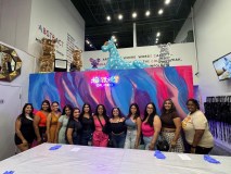 Group of people posing in front of a colorful mural at an art exhibit.